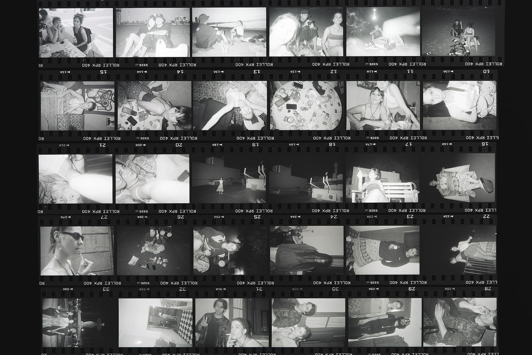 Zdjęcie to odbitka stykowa (ang. contact sheet) negatywów z kliszy czarno-białej Rollei RPX 400, prezentująca 36 pojedynczych klatek filmowych z różnymi ujęciami i scenami.