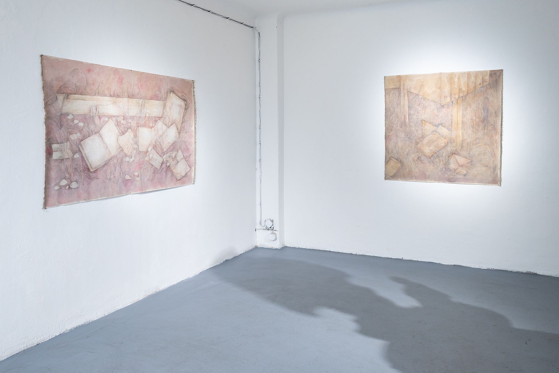 Obraz przedstawia widok z narożnika na galerię sztuki lub przestrzeń wystawową, w której prezentowane są dwa abstrakcyjne obrazy.