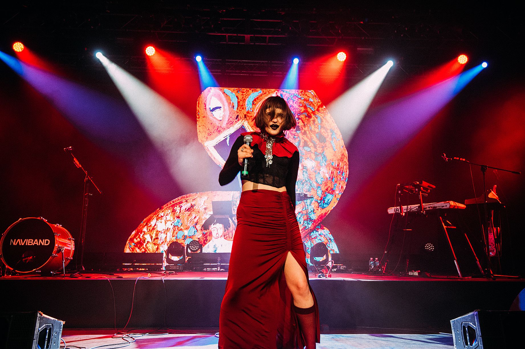 Kobieta  ubrana na czerwono-czarno na scenie zapewne w czasie koncertu