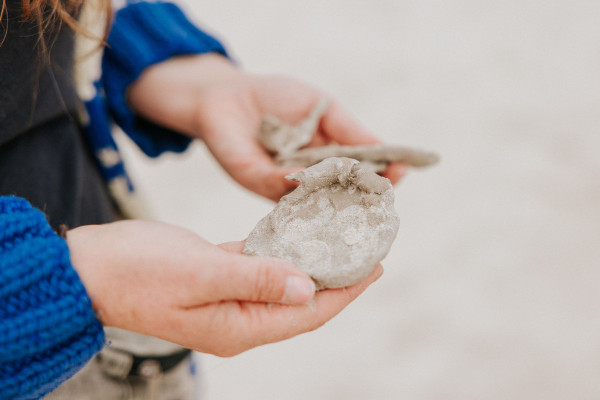 Zbliżenie na dłonie trzymające odlew z gliny lub ciasto?
