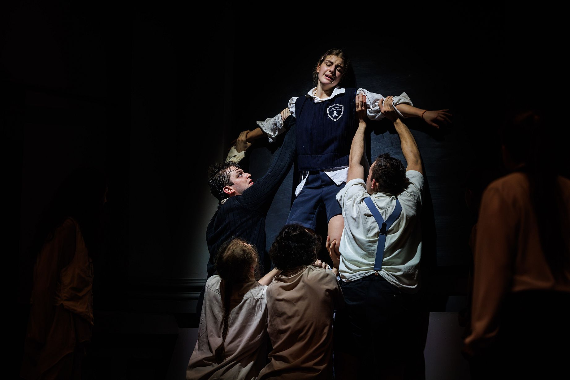 scena w teatrze, czwórka aktorów unosi aktorkę ubraną&nbsp;w strój uczennicy