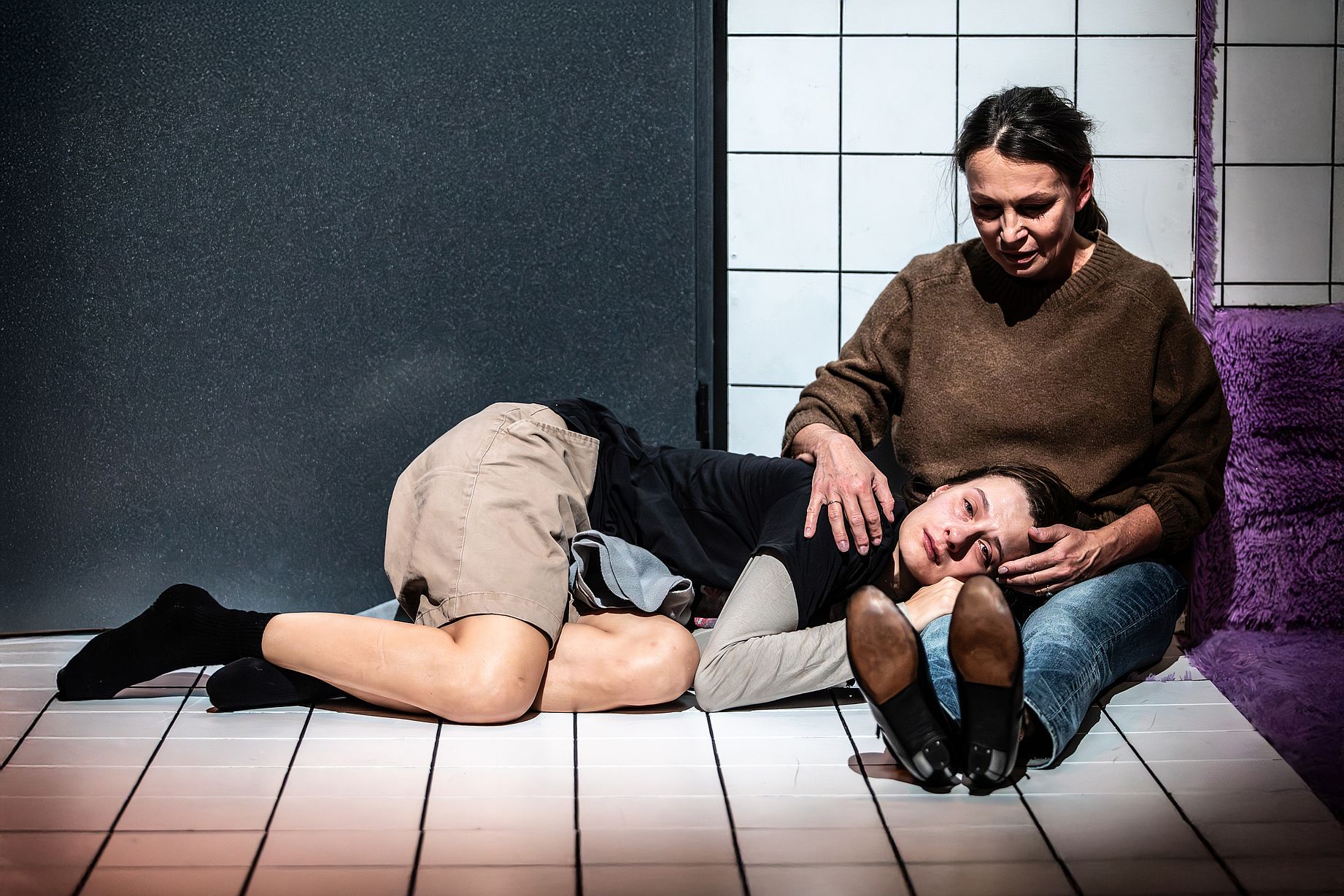 Na zdjęciu widać scenę ze spektaklu „Czas na wielki numer”.  Matka siedzi na podłodze, na jej kolanach leży zapłakana córka