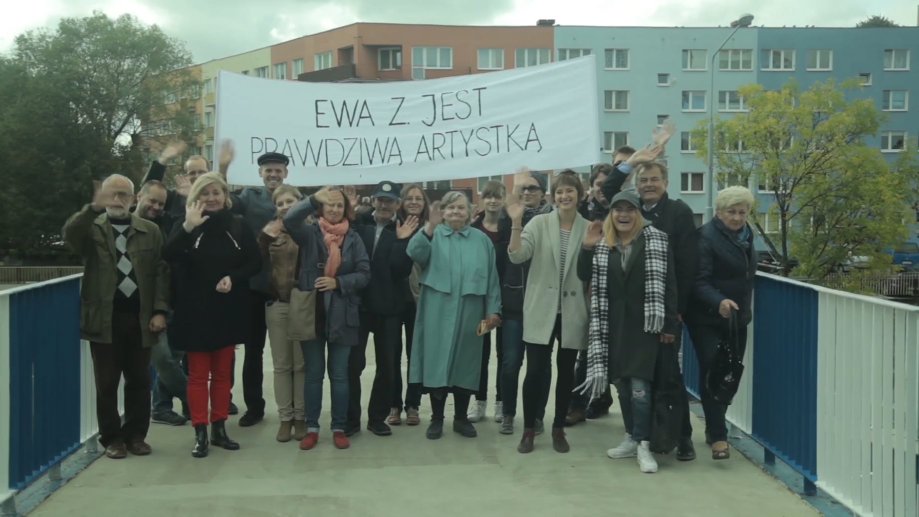 Grupa osób na kłądce nad ulica stoi z transparentem z napisem: Ewa Z. jest prawdziwą artystka