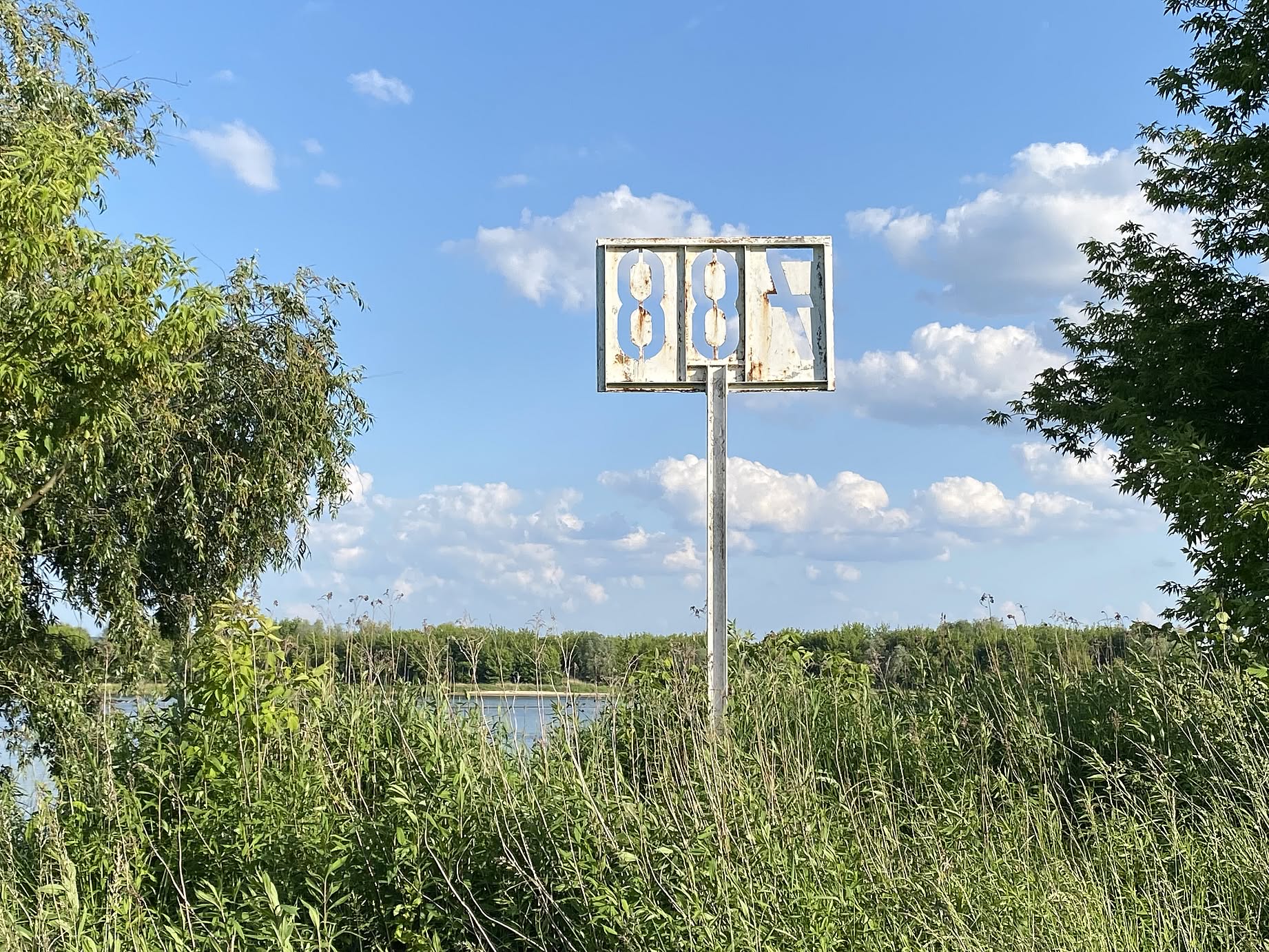 brzeg Wisły, zarośla, rzeka, na brzegu biały znak 788, niebieskie niebo, chmury