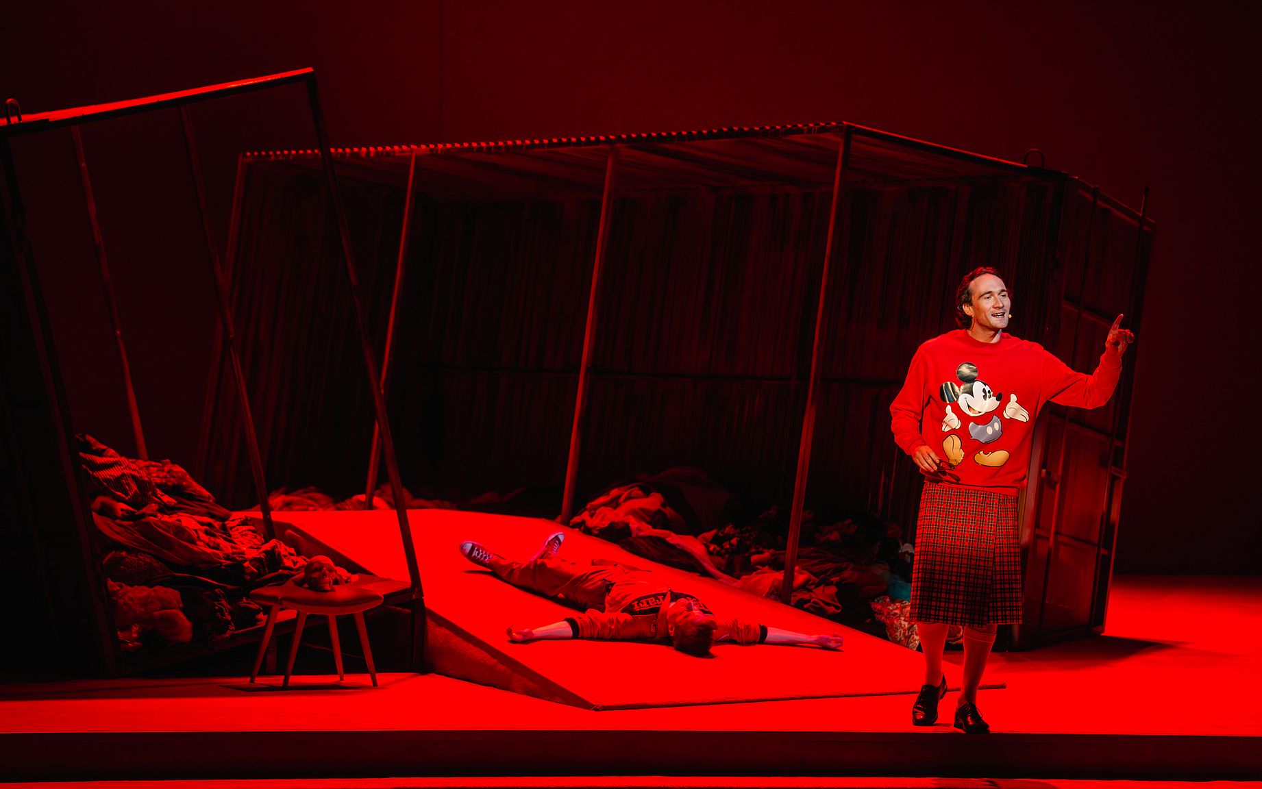 scena w teatrze, mężczyzna w bluzie z myszką miki w spudnicy w szkocką kratę