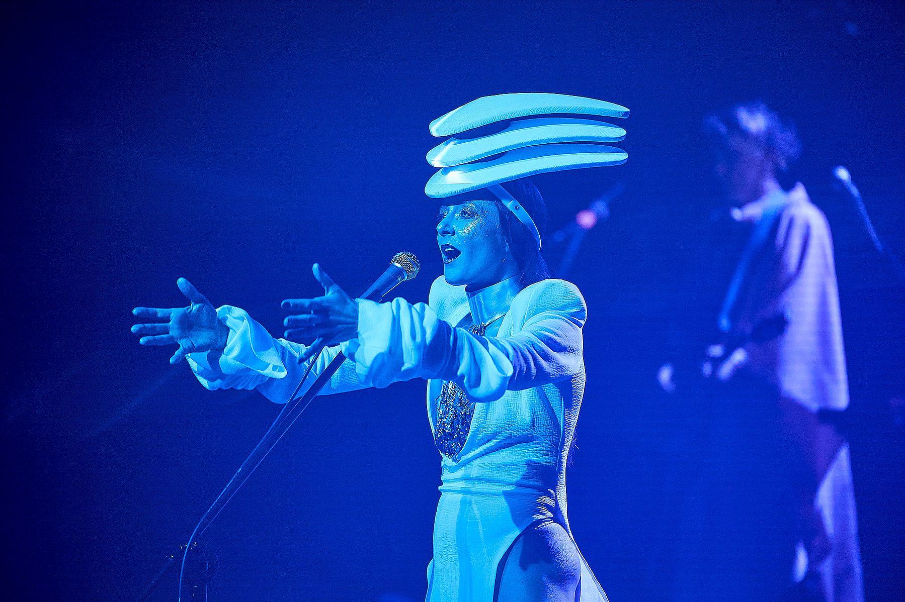 kobieta na scenie w dziwnym nakryciu głowy, niebieskie światło
