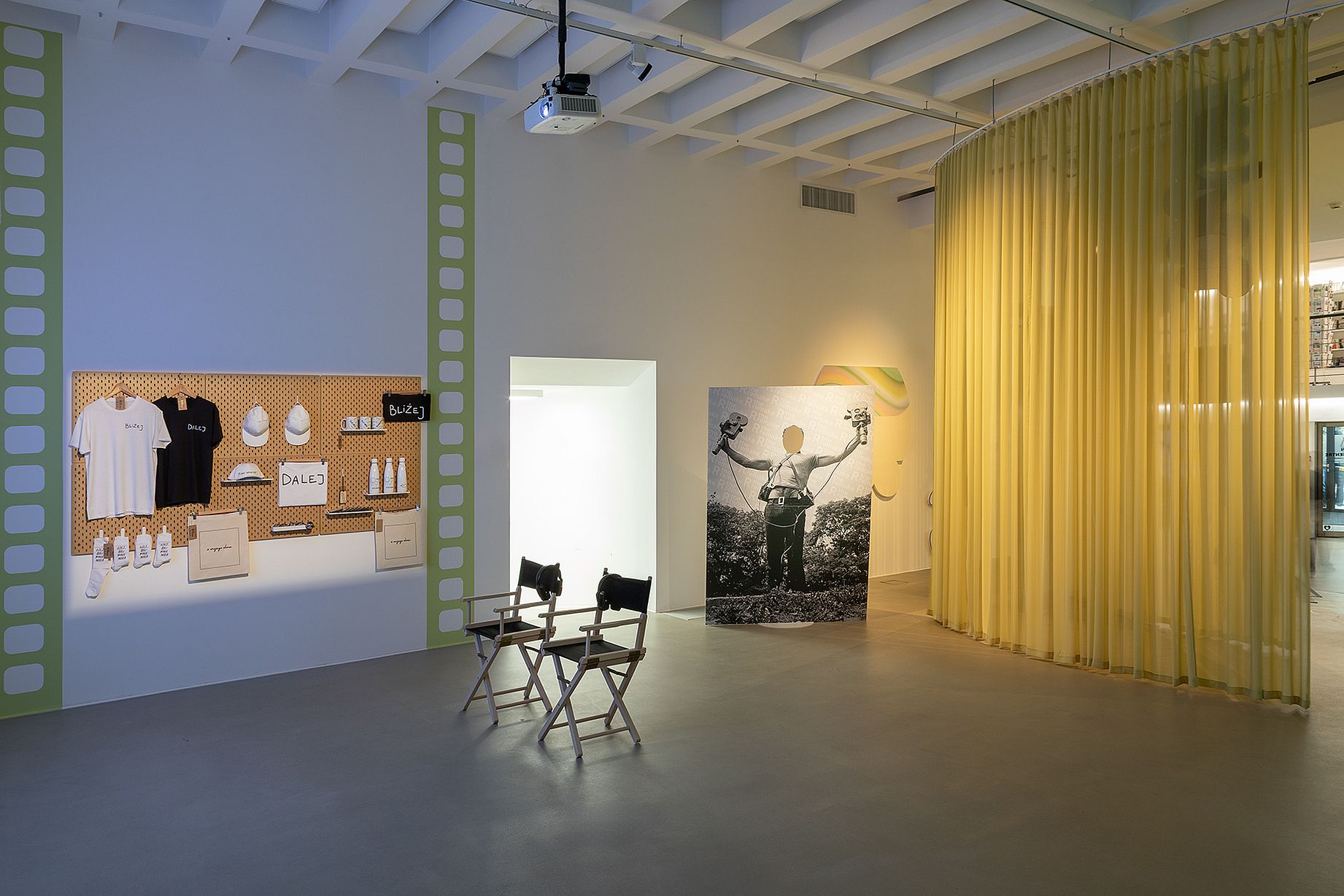 Widok wystawy, kotara, krzesło przed zawieszonymi na ścianie gadzetami