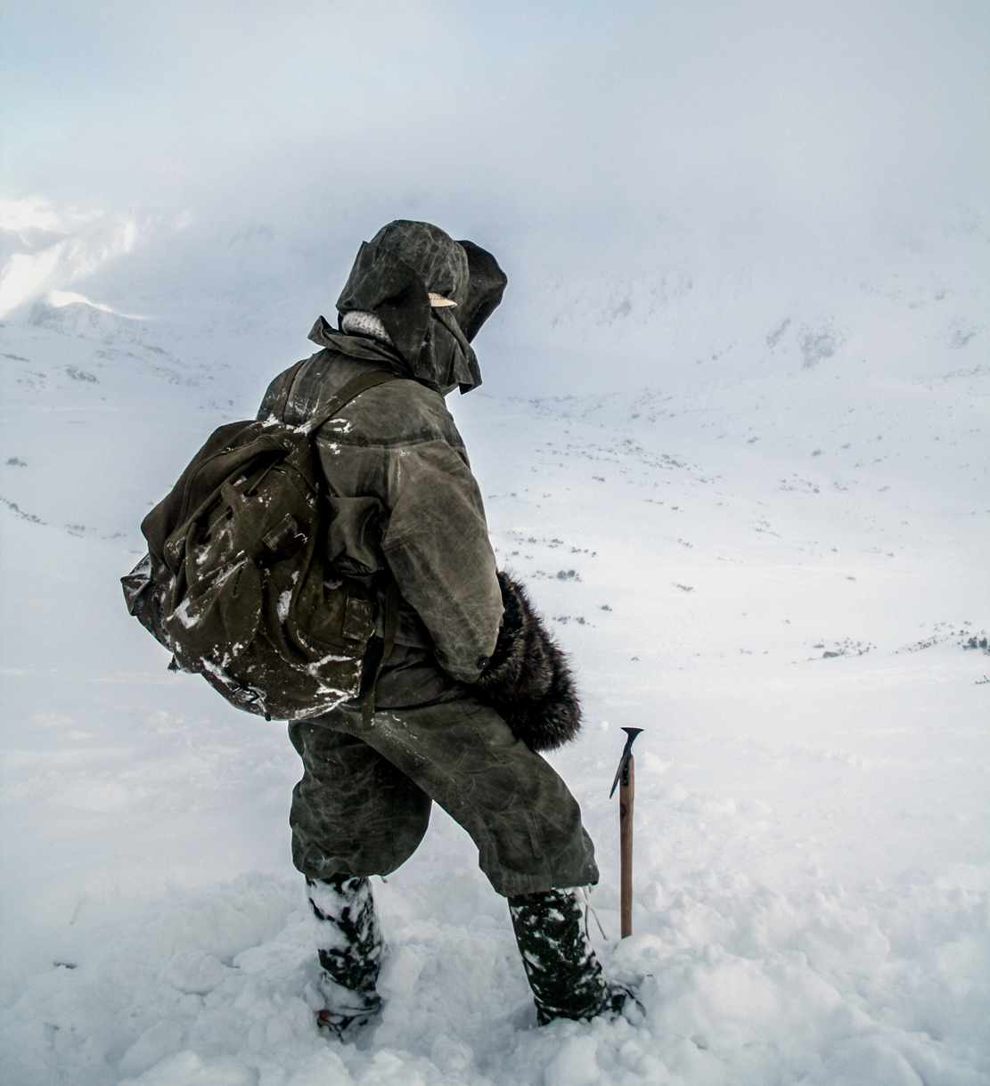 człowiek z plecakiem patrzy na śnieg i góry