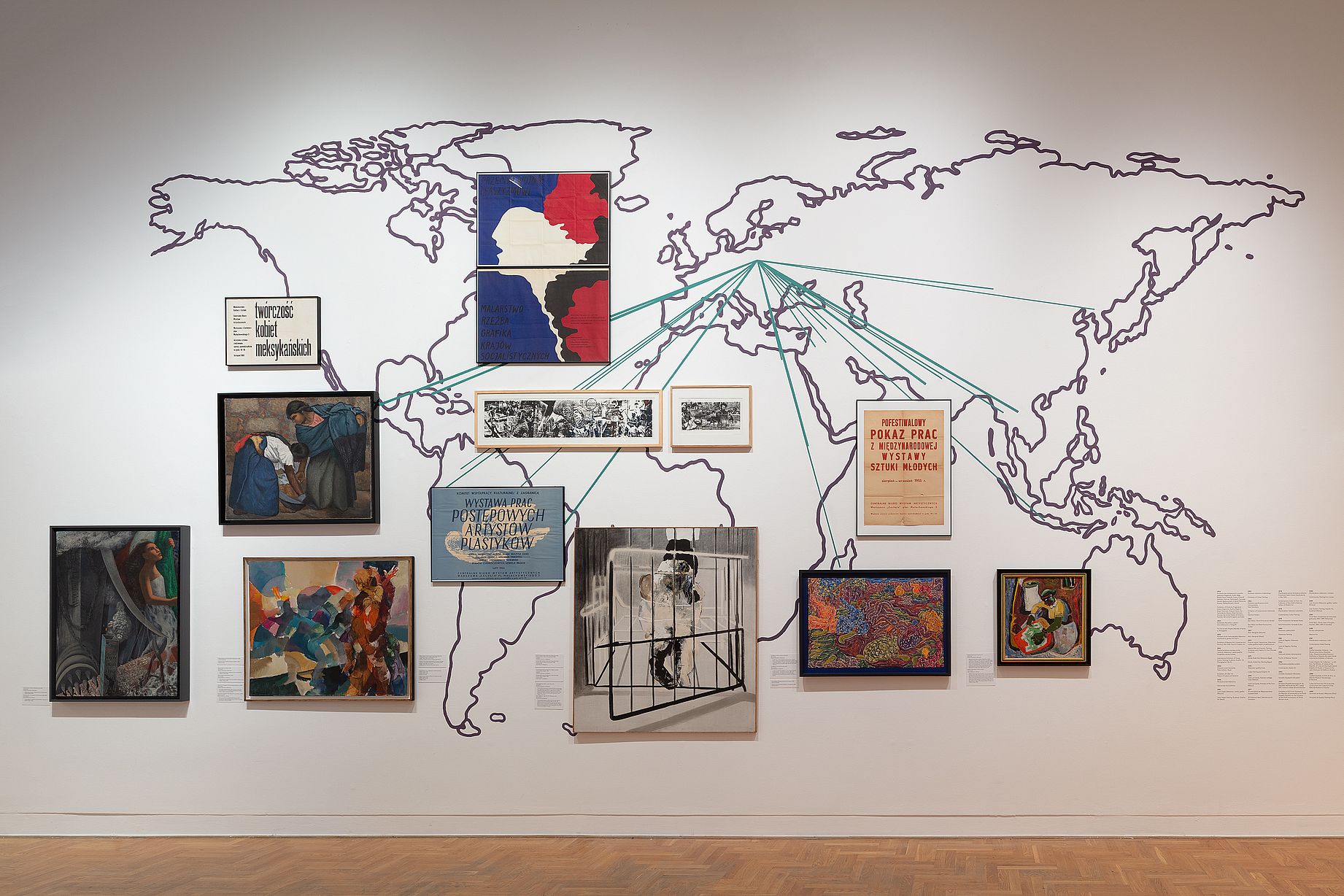 Wielobarwny mural autorstwa kolektywu Aravani Art Project przedstawia kilka kobiet w tradycyjnych strojach, otoczonych dużymi kwiatami i ptakiem, w pomieszczeniu zaaranżowanym z poduszkami i patchworkowymi dywanami na podłodze. 