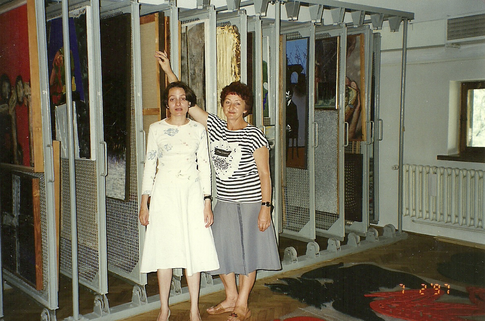 dwie kobiety stoją przy gablotach na obrazy w magazynie muzeum