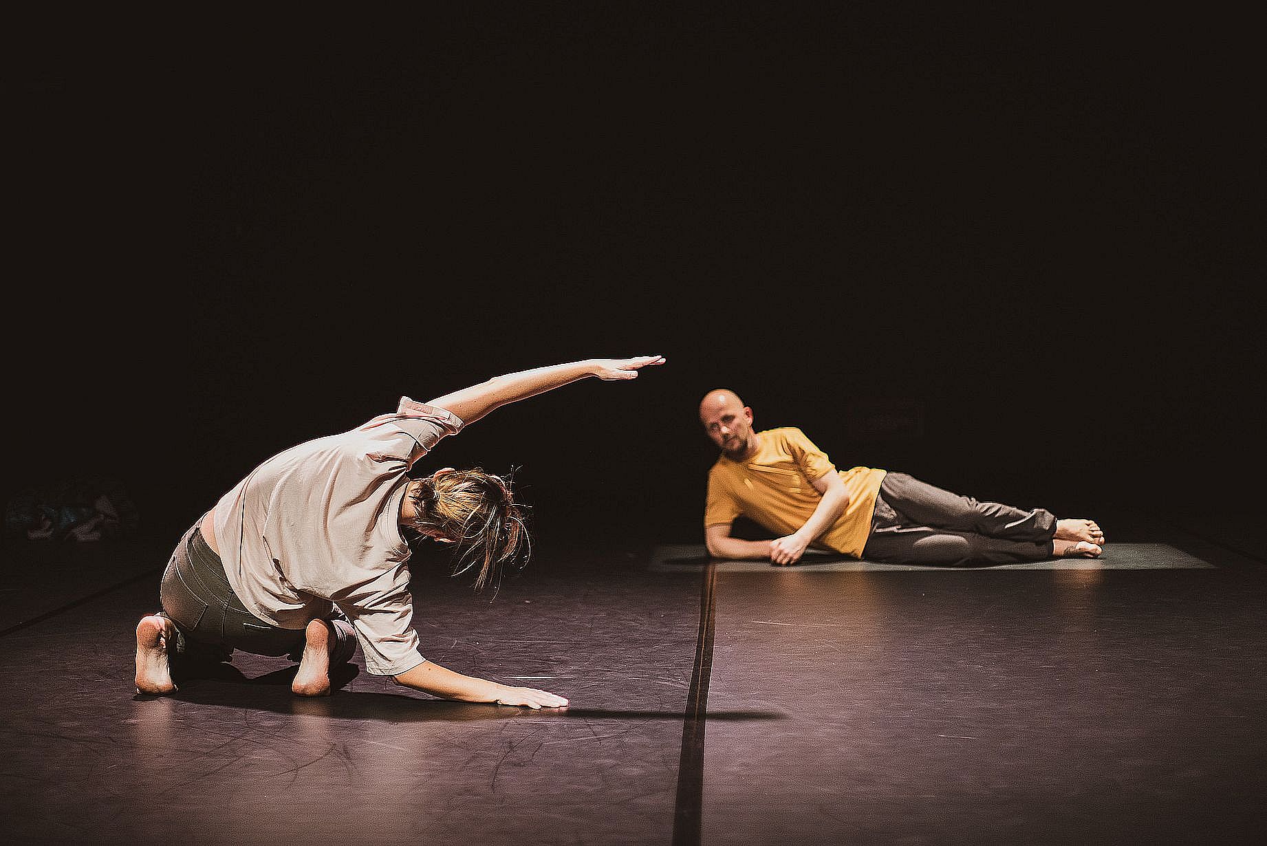 tancerka na scenie wygięta w jedną stronę, w tle tancerz leży na podpartej ręce